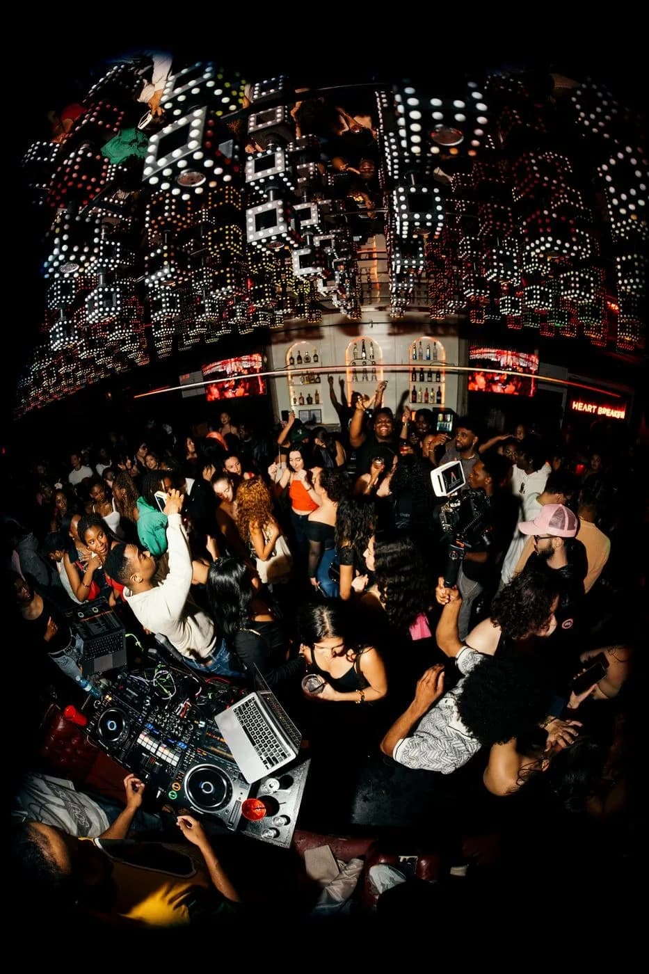 Fisheye view from the DJ booth over a packed club crowd under a ceiling of glowing lanterns