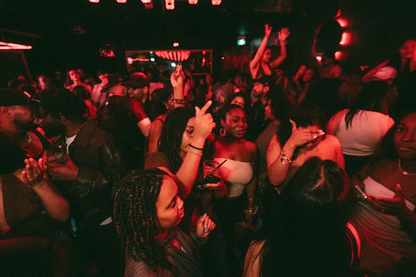 Dance floor packed with people dancing under red club lights