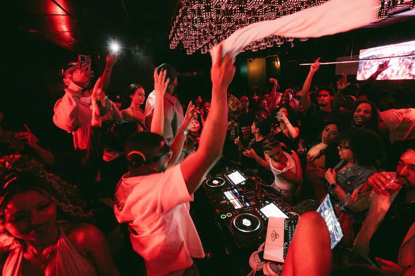 Hands and a towel in the air around the decks under red light